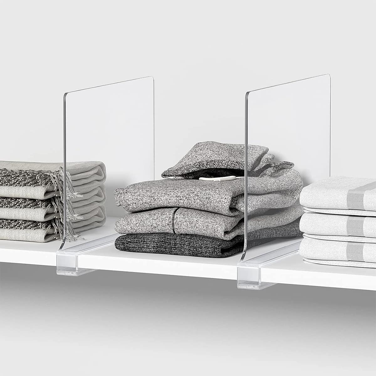 Folded shirts on a shelf with acrylic dividers.