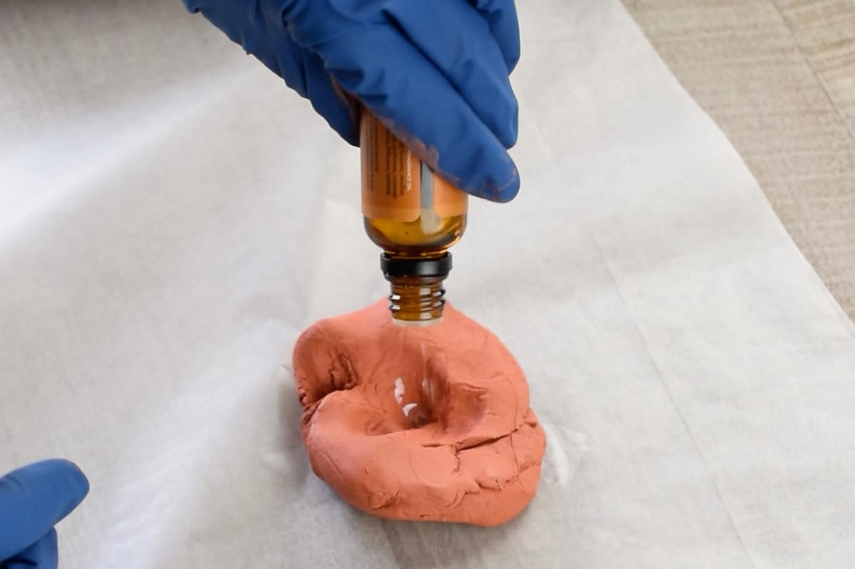 Closeup of adding essential oils to clay for scent.