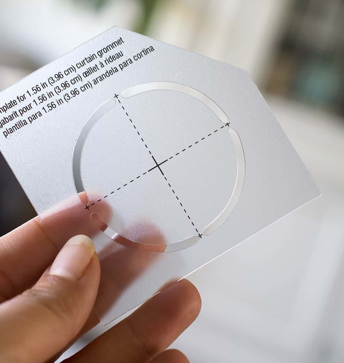 Hand holding up a curtain grommet template.