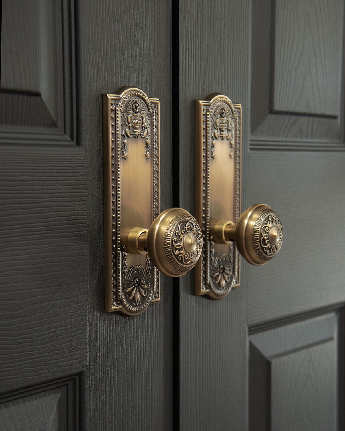 Closeup of antique brass doorknobs with backing plates on double doors.