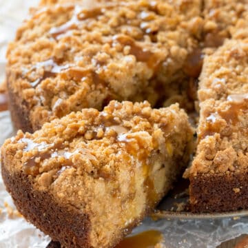A slice of apple crumb cake being removed from the cake with a pie server.