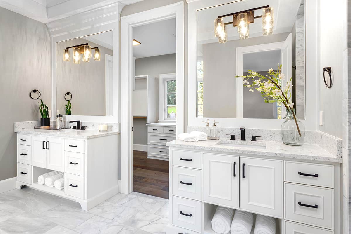 Transitional white bathroom with white tile floors and two separate sink stations.