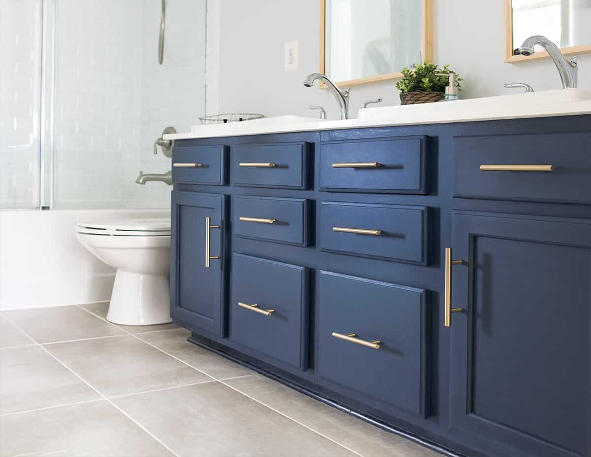 Midnight blue painted double vanity with brass hardware in a light bathroom.