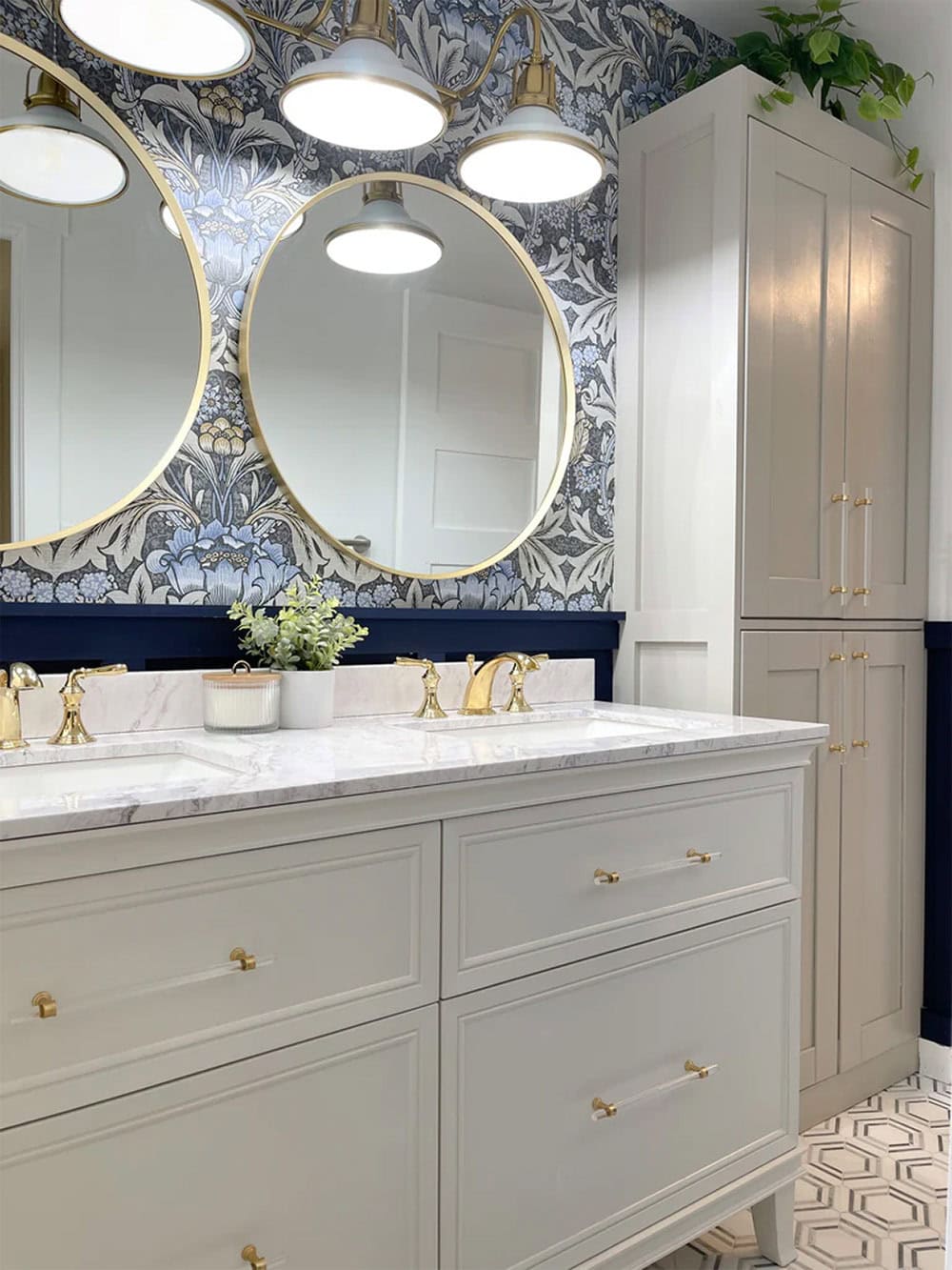 A wallpapered vanity with round mirrors and a patterned tile floor.