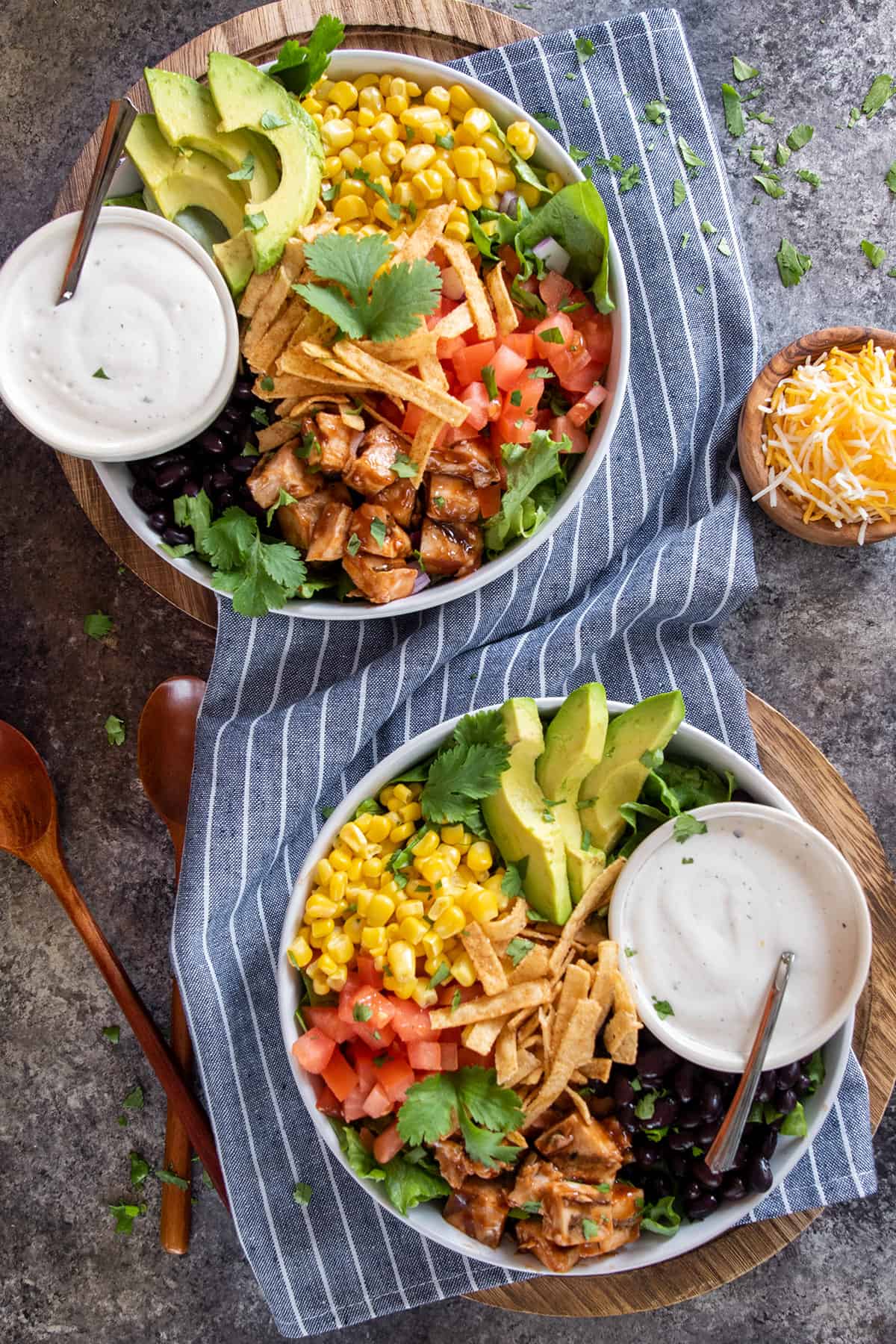 Overhead of two full bowls of BBQ Chicken Salad with ranch dressing on the side.