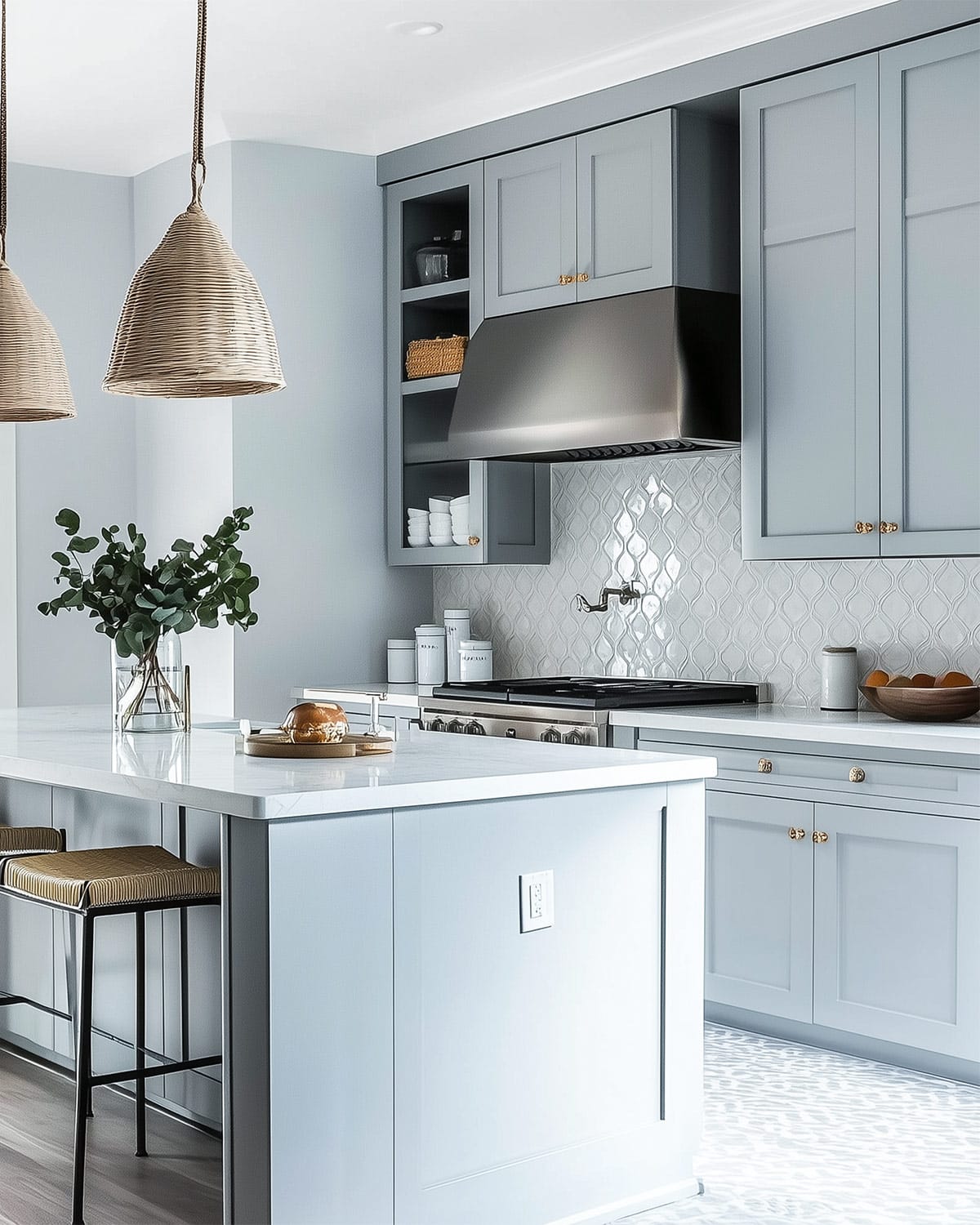 Kitchen with white tile and white countertops featuring Benjamin Moore Pale Smoke cabinets with glass and chrome pulls. Eucalyptus and glass jars as accents.
