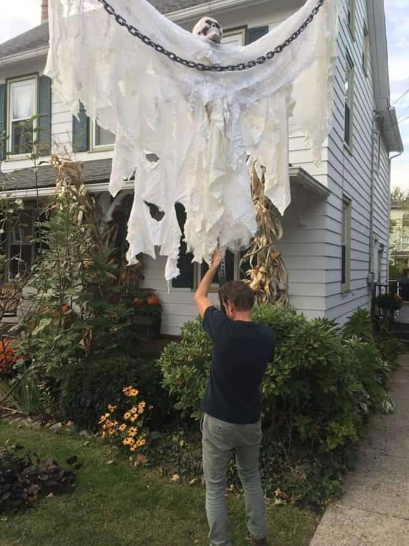 Big guy Halloween decoration with tree roots for hands and a repurposed clown mask face that leaves a BIG impression.