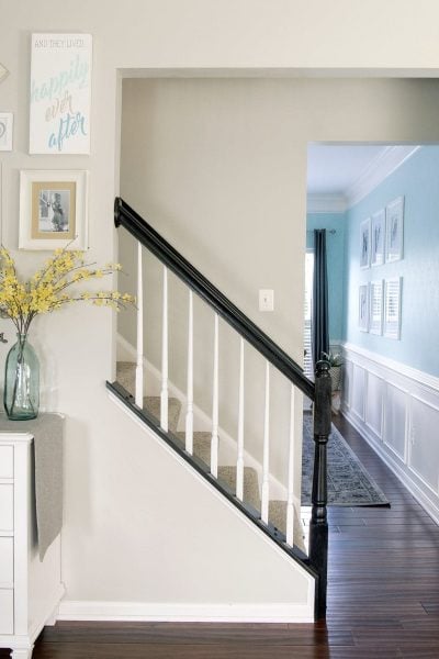 Completed oak painted stair railing with black handrail and white balusters.