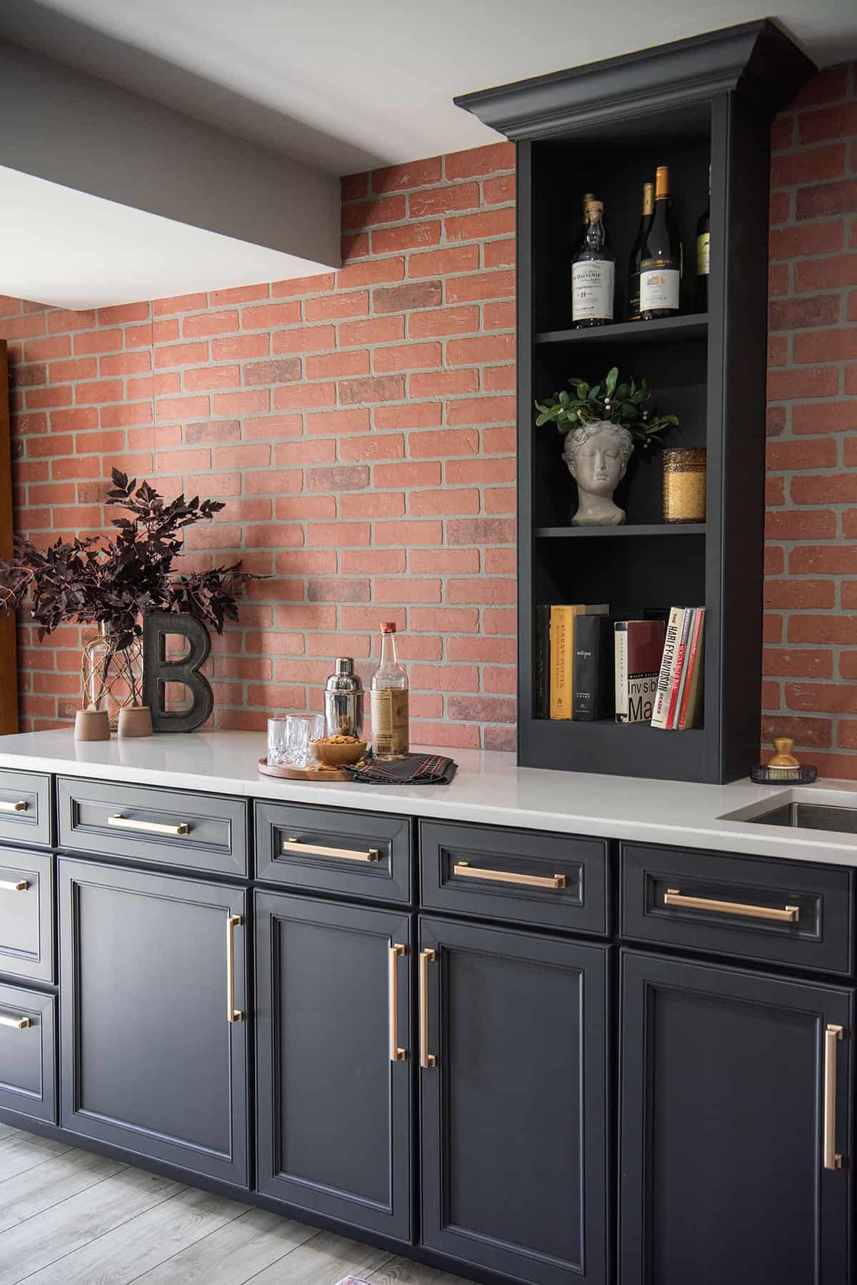 Wet bar with black cabinets, brick wall in a contemporary style for a pub inspired industrial basement makeover.