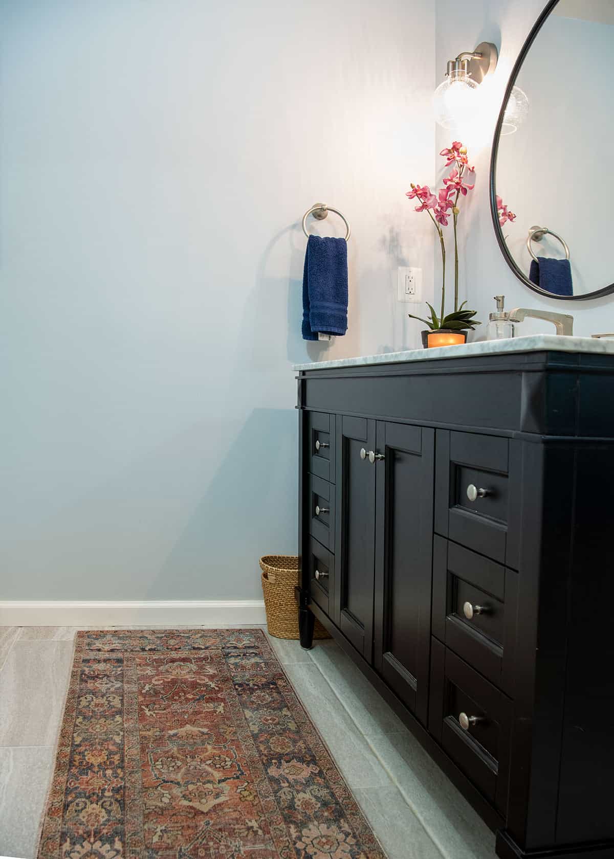 Sideview of a black vanity with red traditional rug and blue walls.