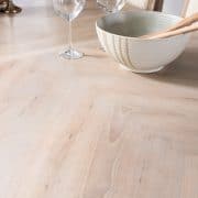 Stripped dining room table after. Wood grain pattern revealed. Wine glasses and white salad bowl with natural accents and wooden utensils for ambiance.