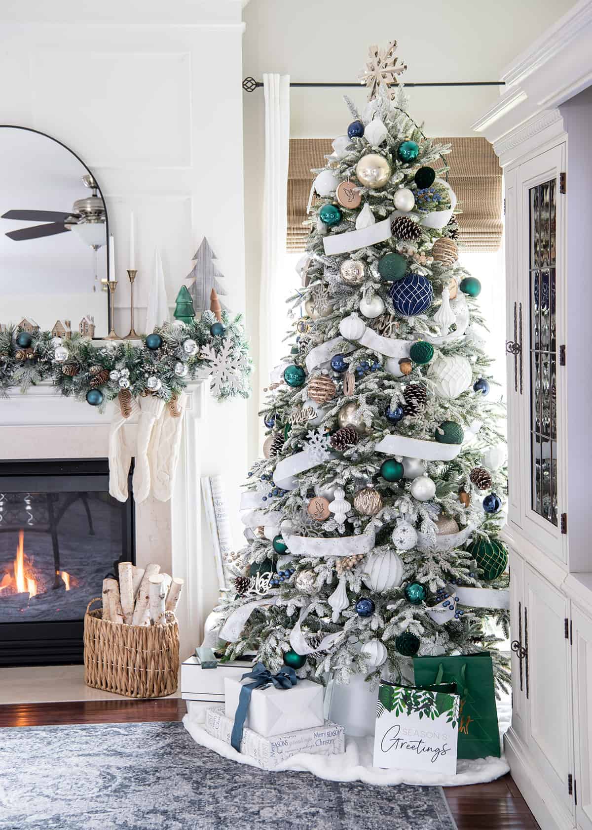 Winter wonderland Christmas tree with hunter green and navy color scheme in a white living room.