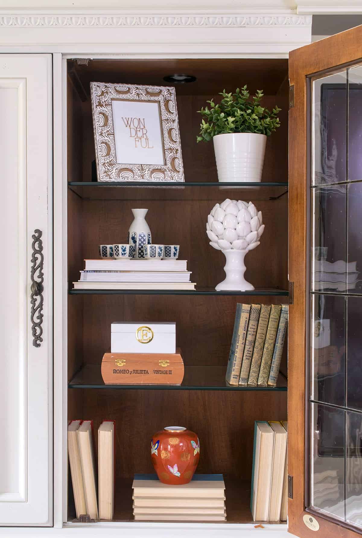 Close up of sentimental items doubled as decor in entertainment center- antique books, sake set and cigar boxes.