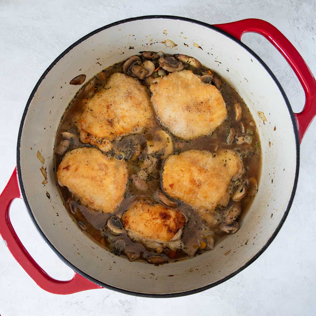 Braised chicken in a pot after searing and adding broth.