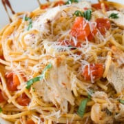 Bruschetta pasta with chicken in a rimmed bowl and topped with balsamic glaze.