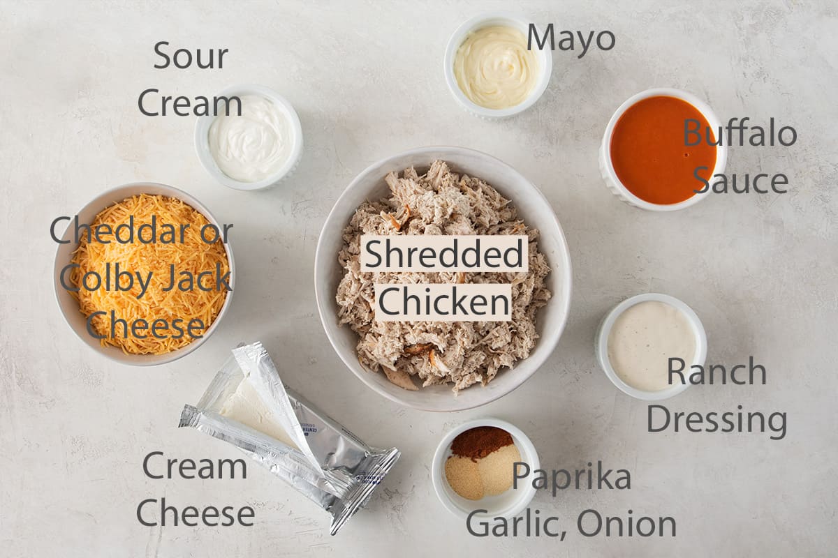 Ingredients for buffalo chicken dip laid out with text labels.