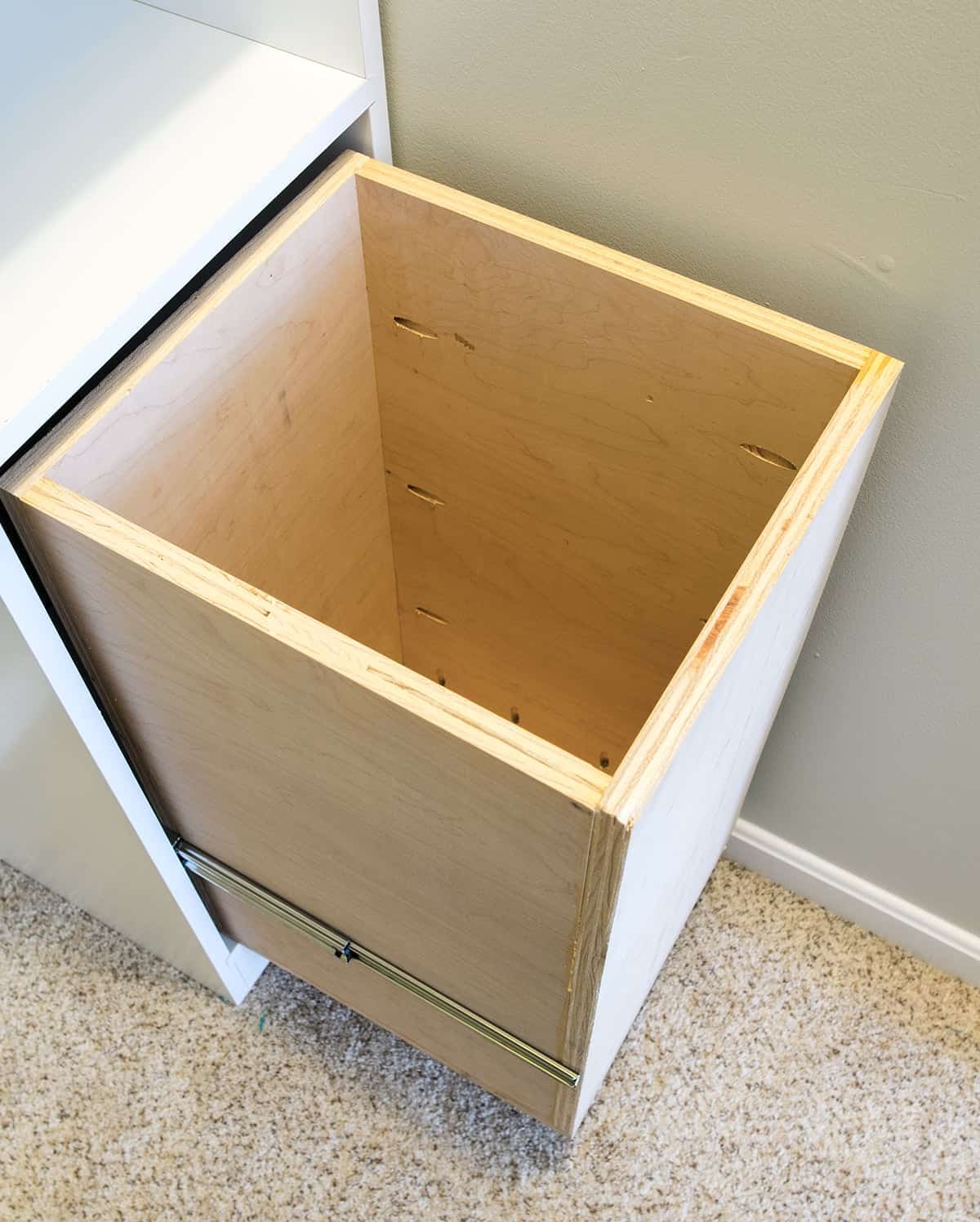 Built-in laundry basket using plywood in white custom bedroom closet.