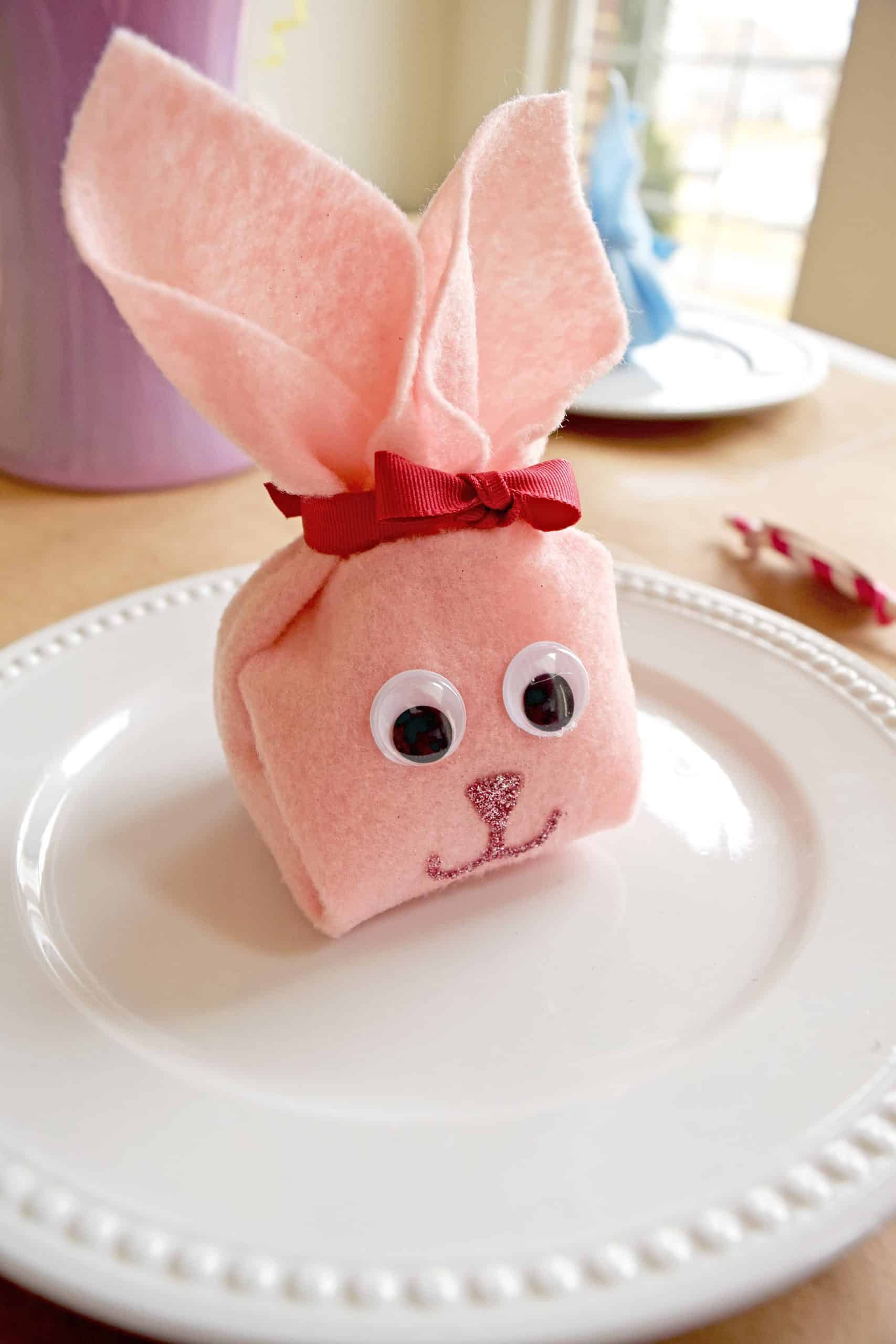 Pink DIY felt bunny pouch with googly eyes on white plate.
