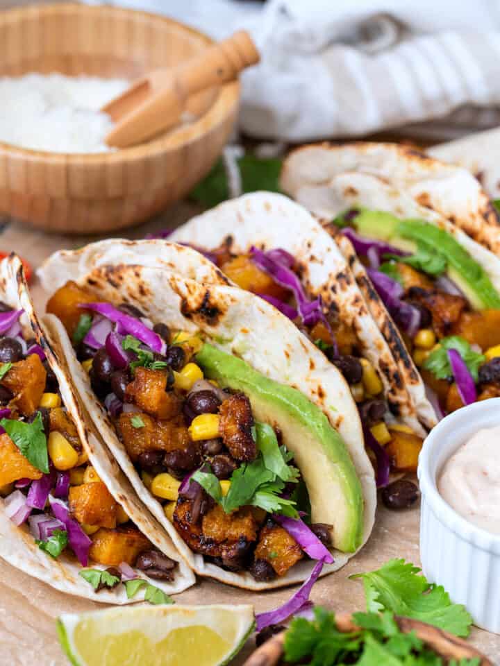 Side view of roasted butternut squash tacos in a tortilla with filling inside.