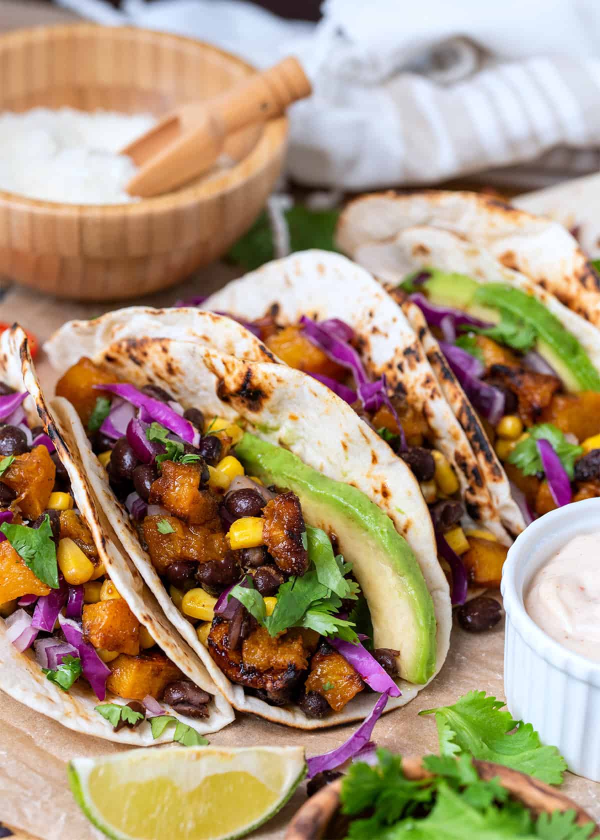 Side view of roasted butternut squash tacos in a tortilla with filling inside.