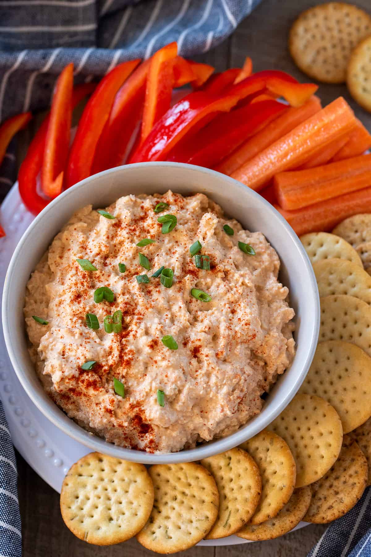 Top-down view of Cajun imitation crab dip in a bowl with crackers, carrots, and peppers around it as dippers.