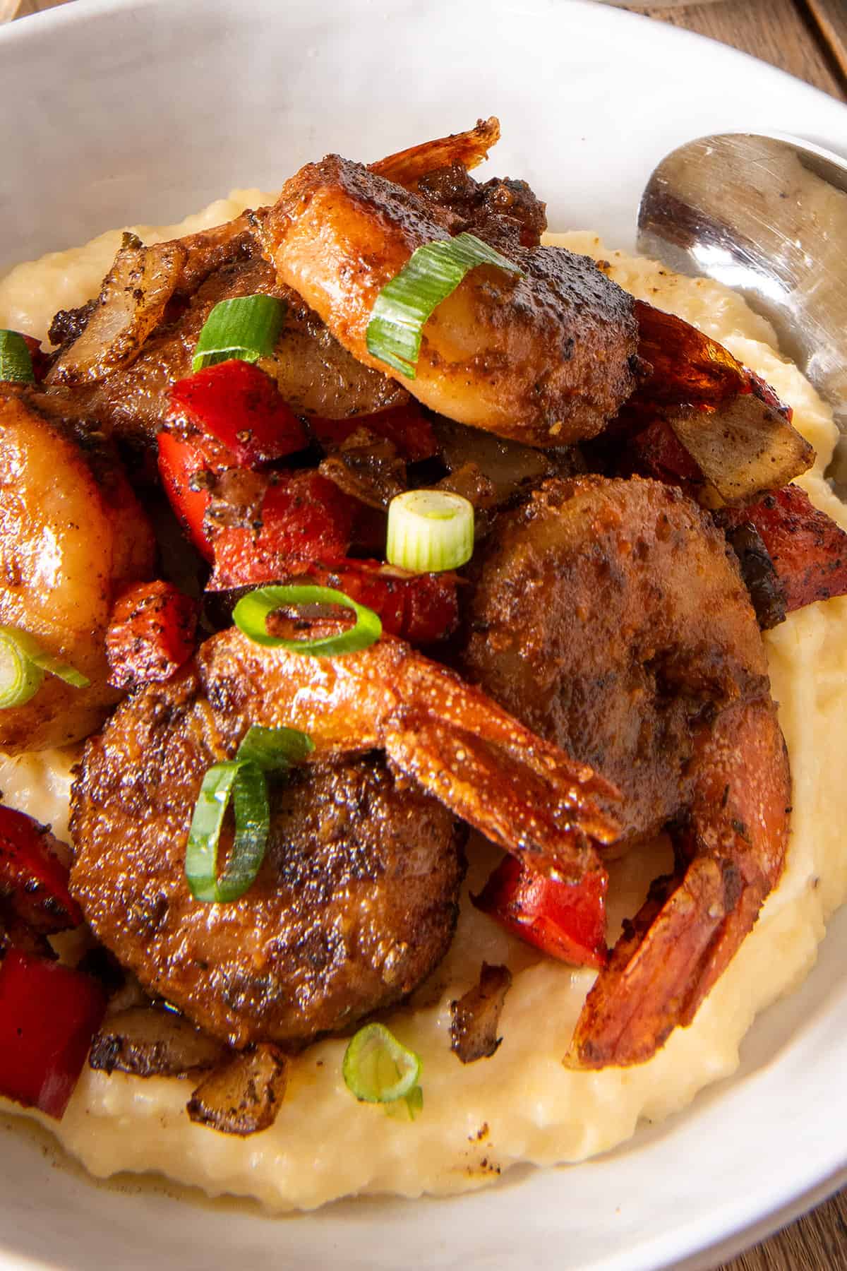 Closeup of a pile of seasoned shrimp over top of cheese grits.