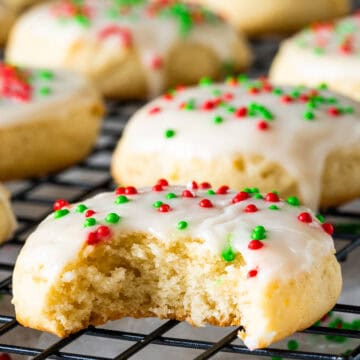 Close up of a sour cream cookie with red and green sprinkles and a bite taken out.