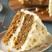 Slice of homemade carrot cake on a plate with walnuts sprinkled on top