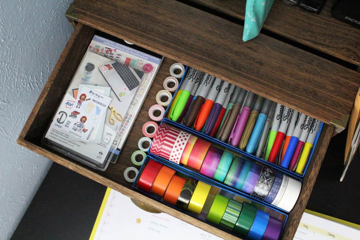 Open drawer with markers and tape in boxes.