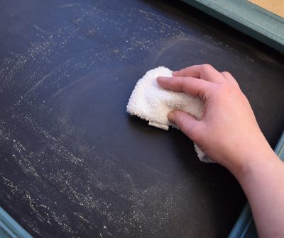 Woman seasoning a chalkboard with a dry rag and chalk.