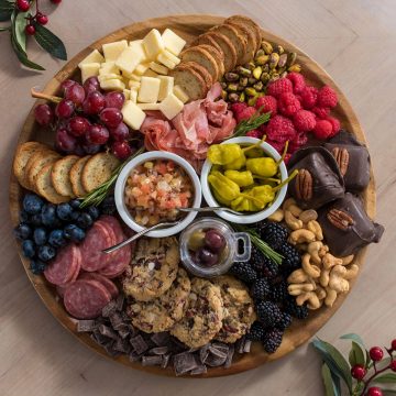 A charcuterie board with cured meats, cheese, and snacks on a wood background.