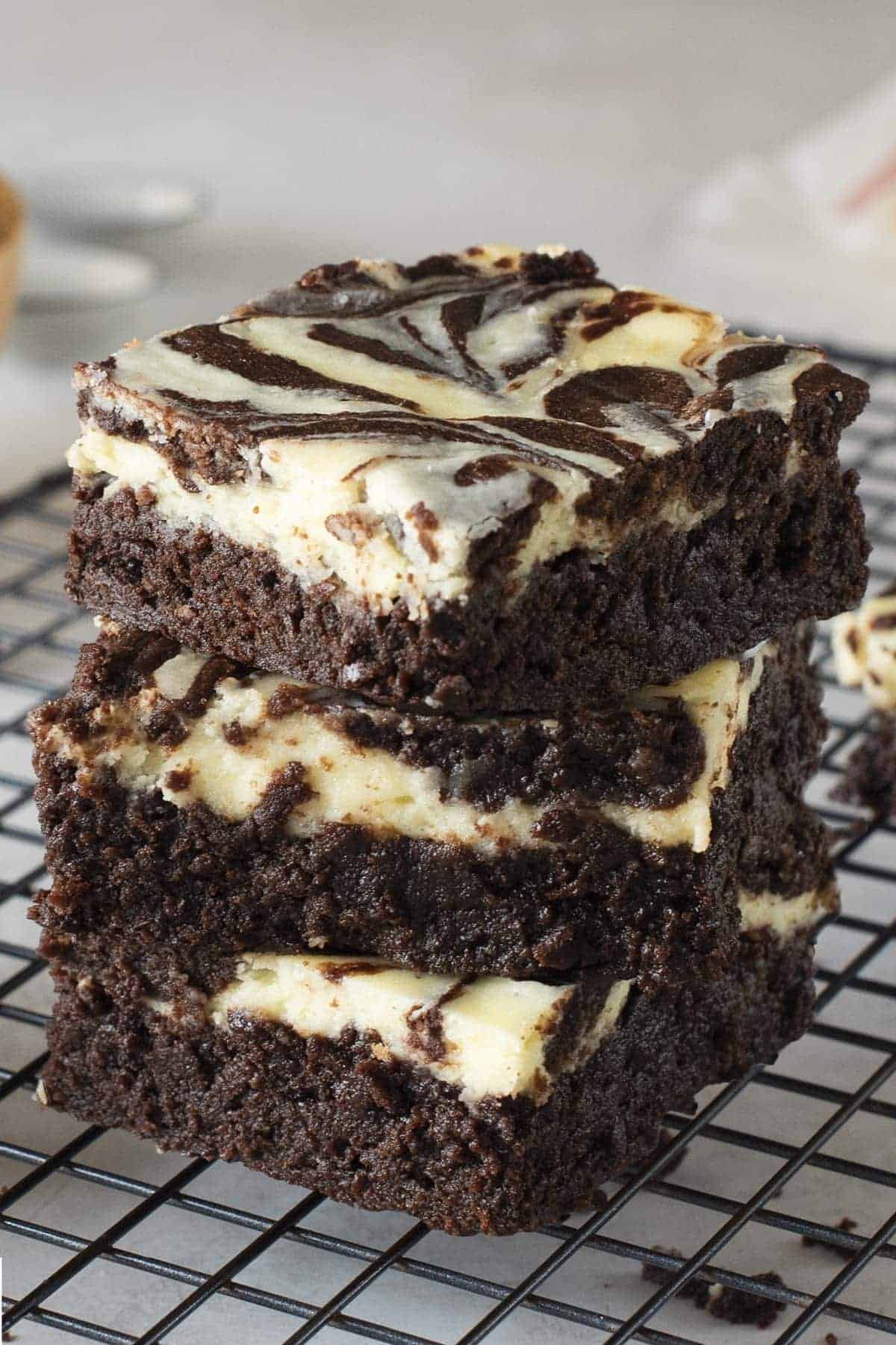 Cheesecake Brownies stacked 3 high on top of a cooking cooling rack.