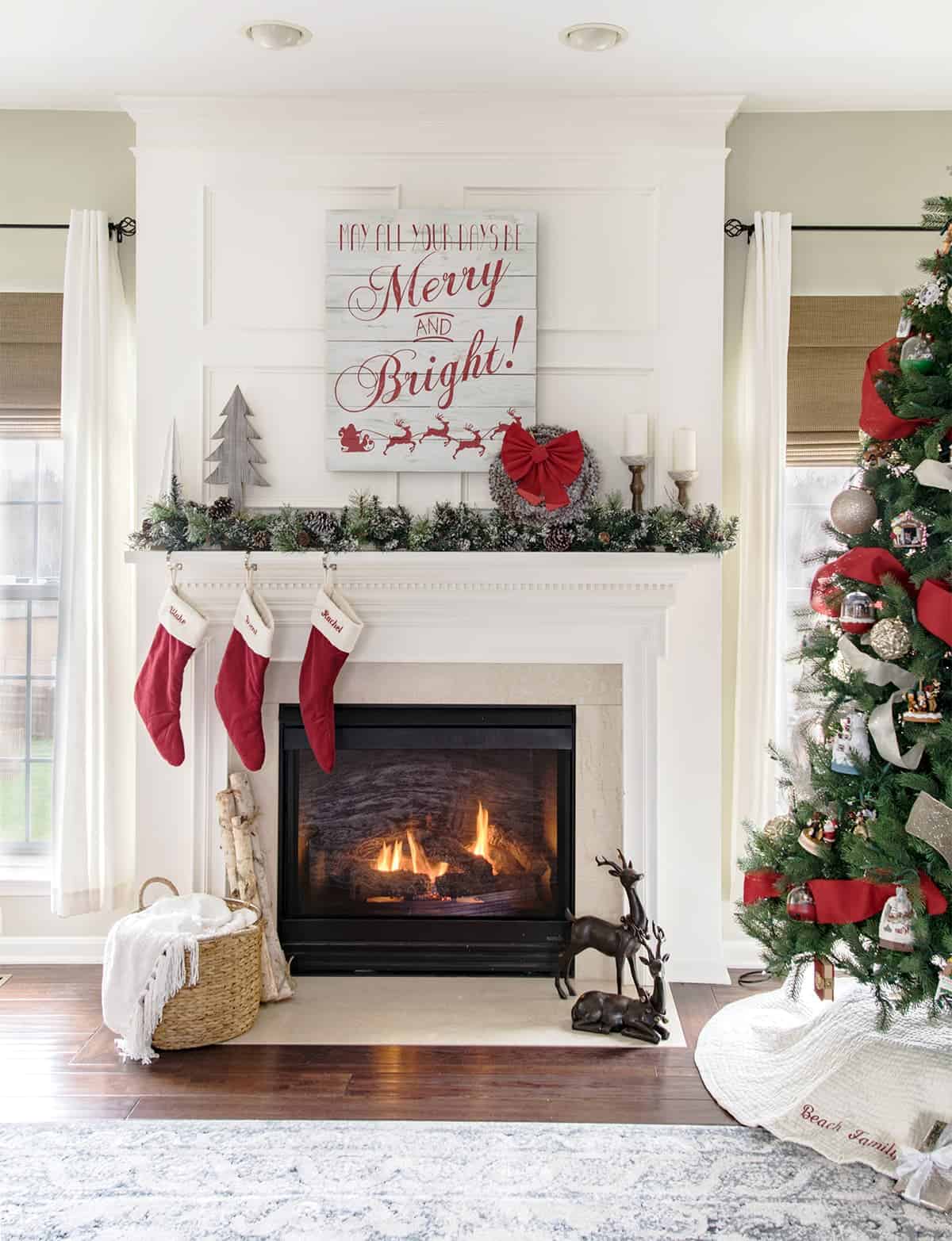Traditional Christmas mantle and living room decor with garland, stockings and Christmas tree.