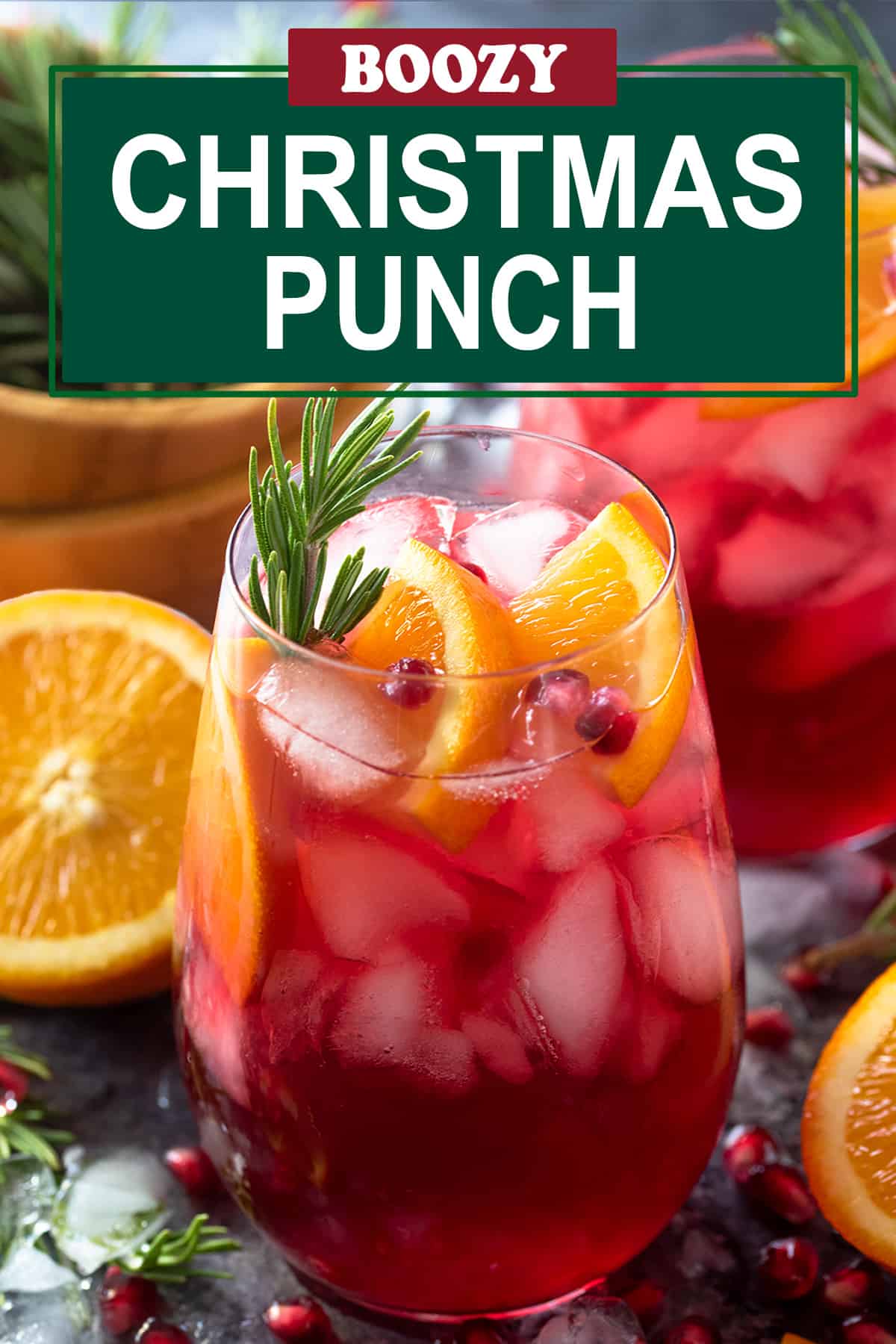 Glass of Christmas Punch garnished with orange slices, pomegranate seeds, and rosemary sprigs. Post title overlay.