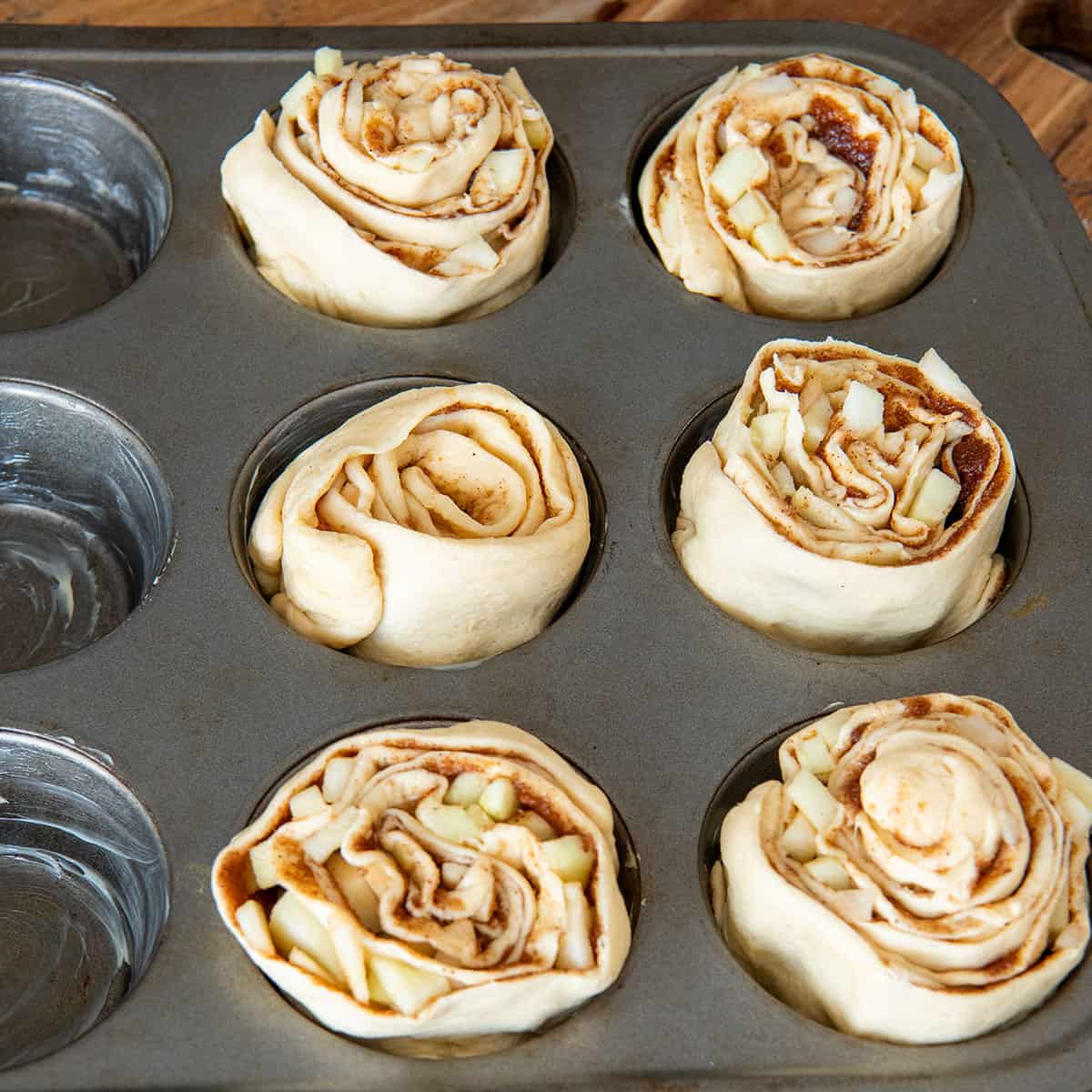 Cinnamon rolls in a muffin tin before baking.