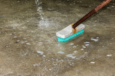 Cleaning floor with push broom.