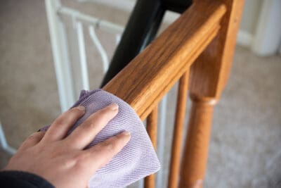 Cleaning stair ballusters with a damp rag.