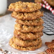 Coconut Pecan Cookies stacked seven high with shredded coconut and whole pecan scattered around.