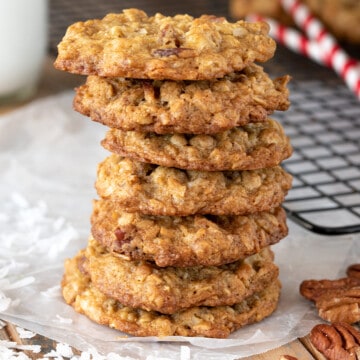 Coconut Pecan Cookies stacked seven high with shredded coconut and whole pecan scattered around.