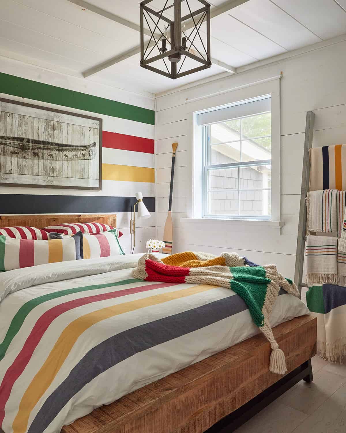 Shiplap planks painted in a classic color block technique inspired by Hudson Bay is provides a cheerful bedroom backdrop.