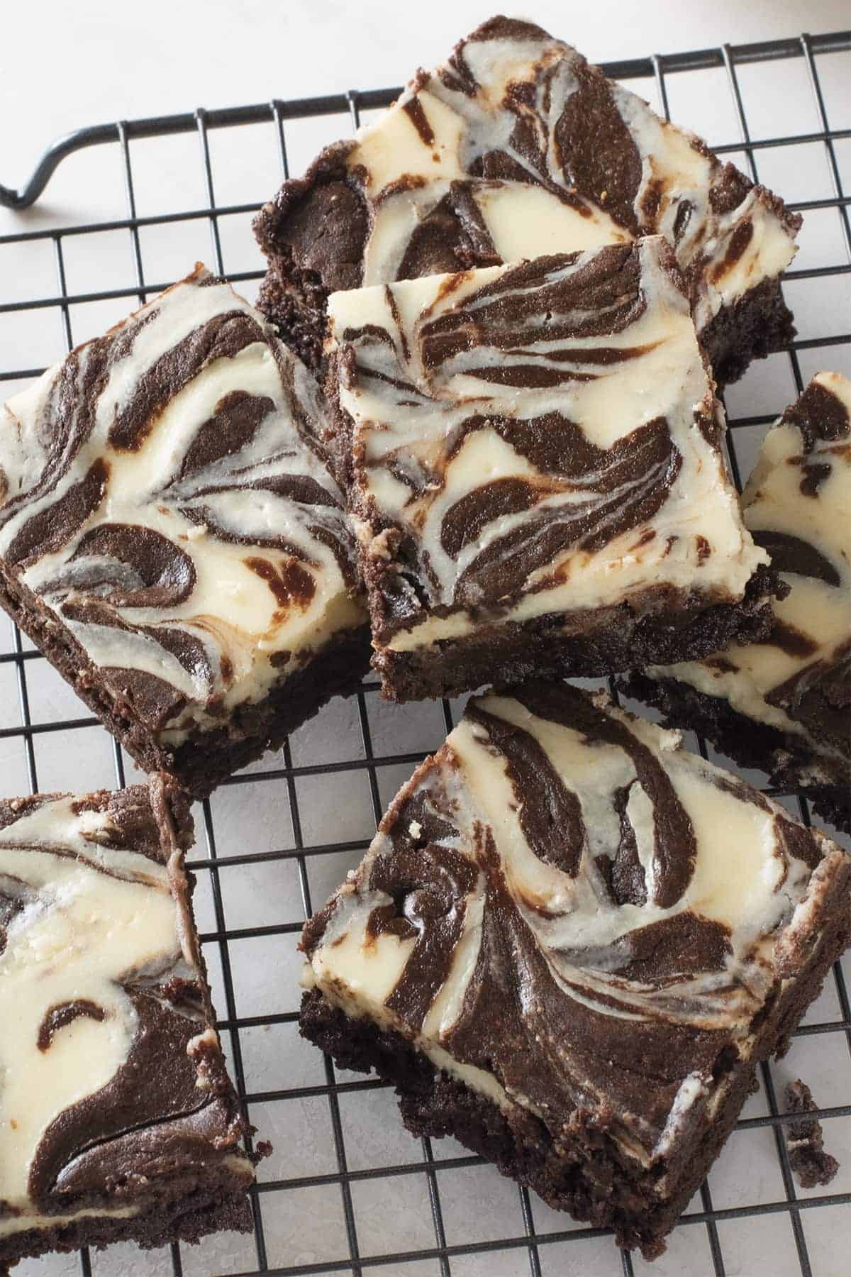 Cream Cheese Brownies laid out on a sheet and stacked to show the texture and marbling.
