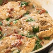 Keto Tuscan Chicken Recipe with Coconut Milk. Spinach, seasoned chicken and sun-dried tomatoes in a pan.