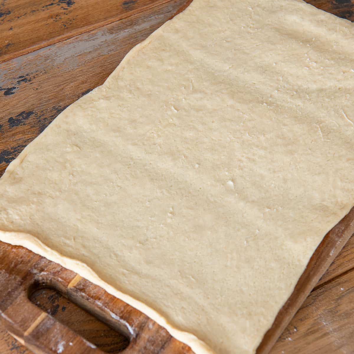 Crescent roll dough rolled out on floured board.