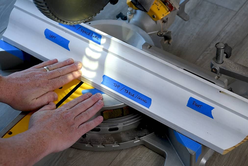 A crown molding board with labels on it showing the top and fence to show how to seat the board for cutting.