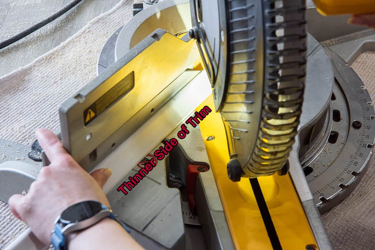 Closeup of a miter saw cutting a piece of trim wood.