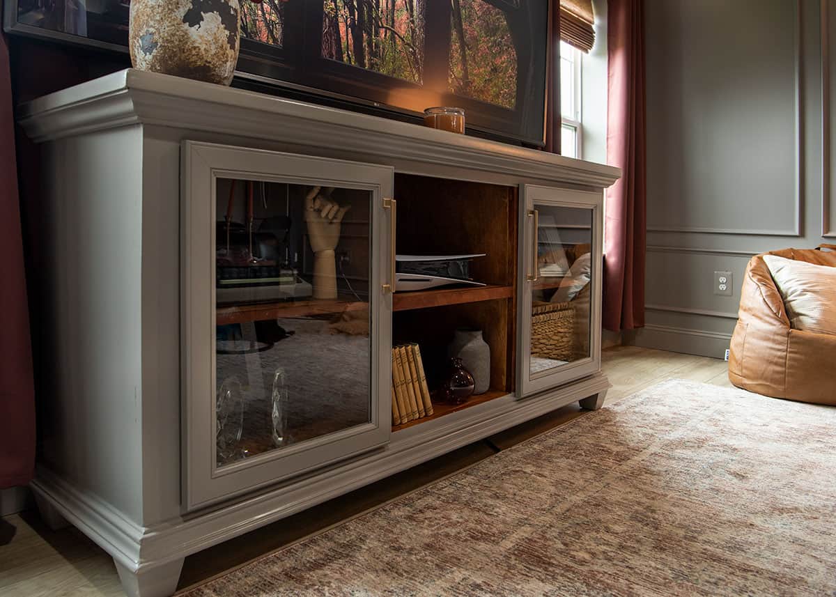 A styled media console with a dark academia decor and painted furniture mood.
