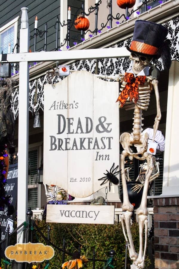 Halloween front porch decor Dead and Breakfast Inn sign with costumed skeletons.