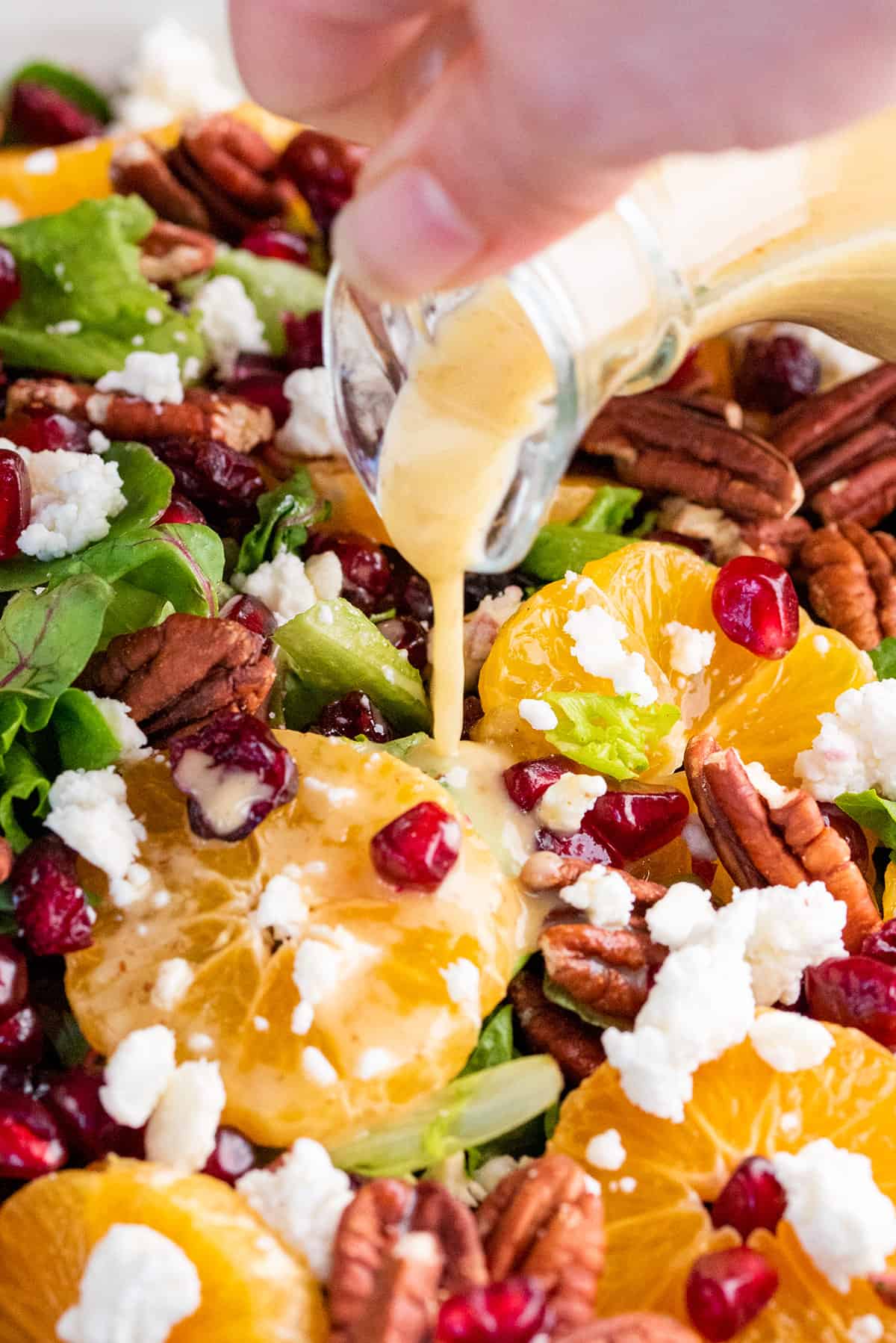 Maple Dijon dressing being poured over a winter fruits salad.