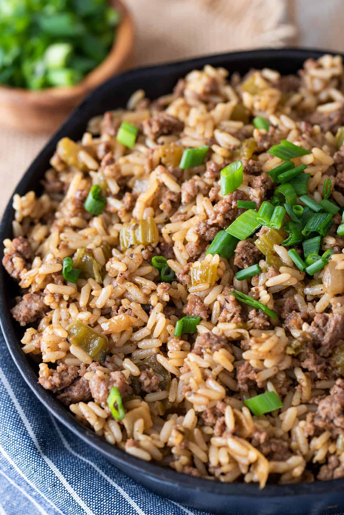 A cast iron skillet with dirty rice recipe in it topped with green onions.