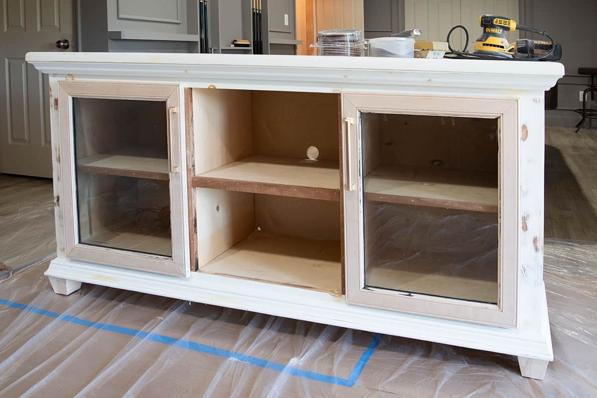 A tv credenza with six cubbies and glass doors being prepped for painting.